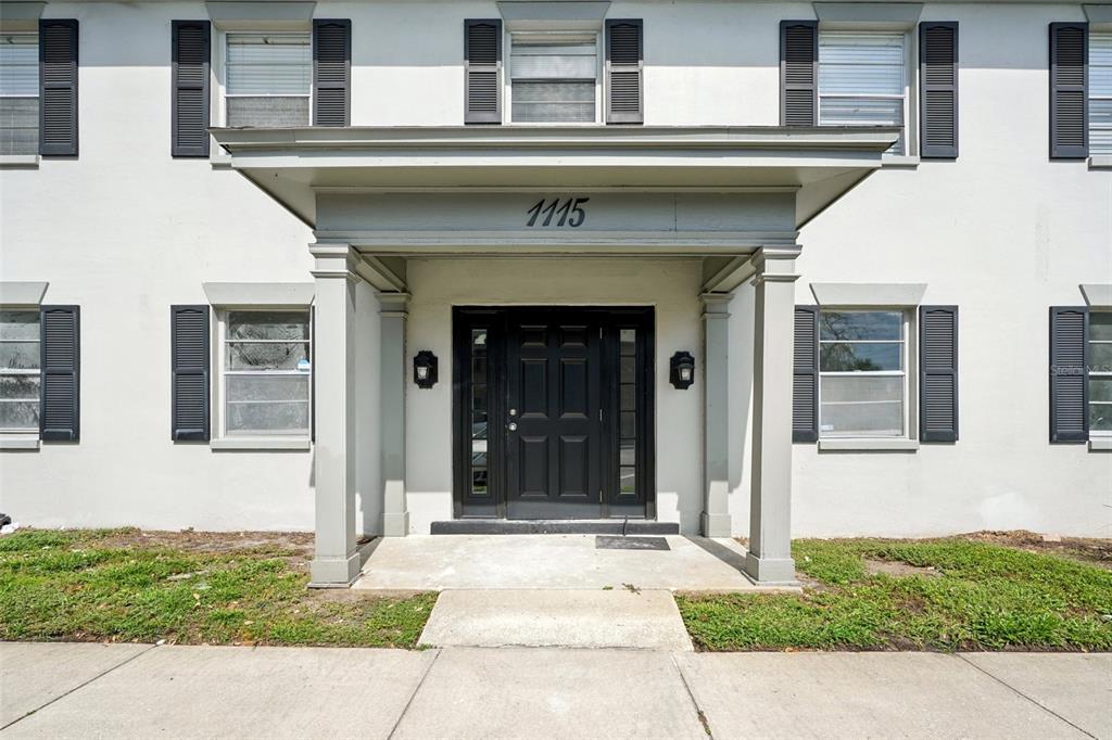 The exterior of a two-story building features a covered entrance with a black front door — 1115 RUE DES CHATEAUX UNIT 2A, SOUTH PASADENA, FL