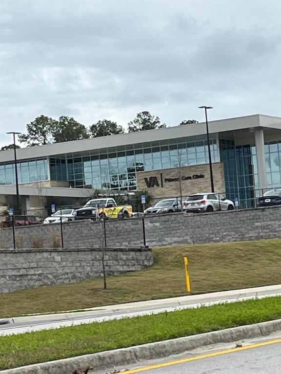A modern VA Primary Care Clinic building stands behind a stone retaining wall and parking lot — 5881 SW 34TH STREET, GAINESVILLE, FL