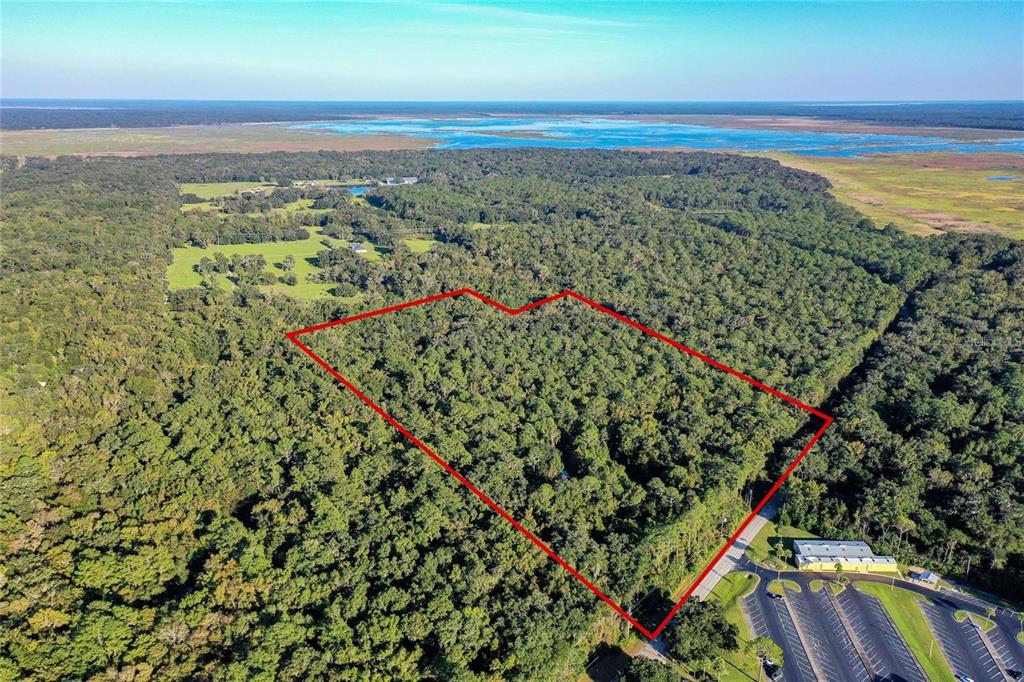 An aerial view shows a wooded plot of land outlined in red near a parking lot — 5881 SW 34TH STREET, GAINESVILLE, FL