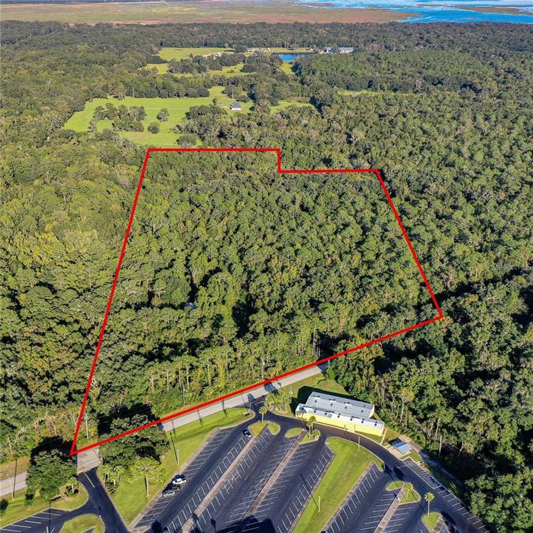 An aerial view shows a wooded lot outlined in red next to a paved parking lot — 5881 SW 34TH STREET, GAINESVILLE, FL