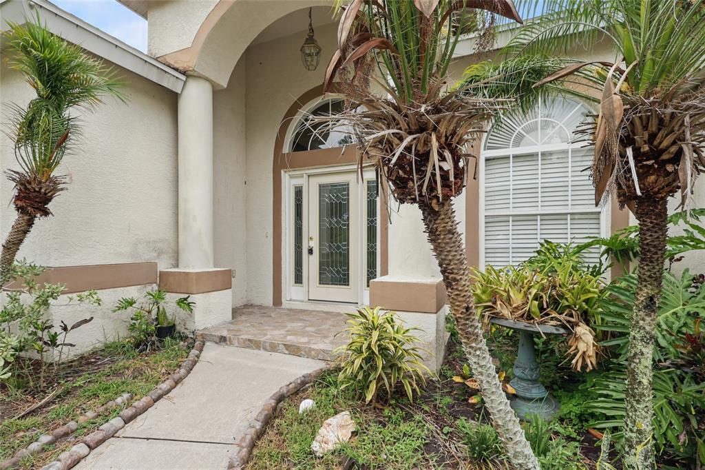A concrete walkway leads to a front entrance with a glass-paneled door and arched window — 4510 BRAZILNUT AVENUE, SARASOTA, FL