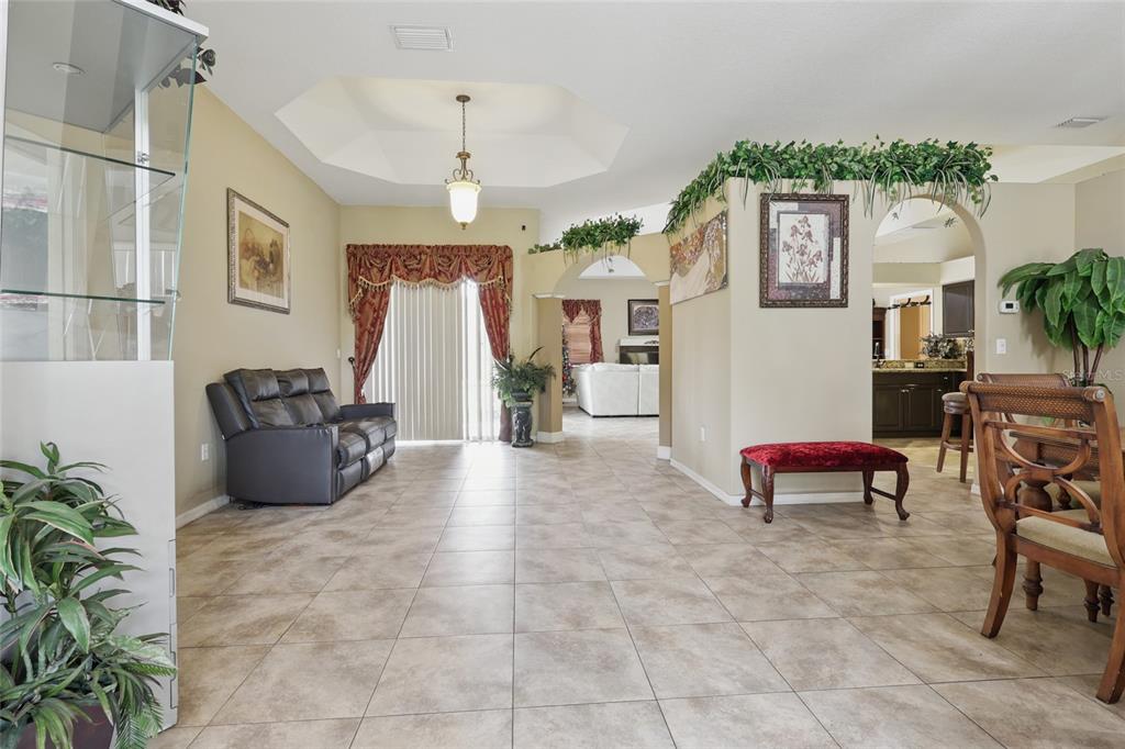 A tiled living area features a tray ceiling, arched doorways, and a dark leather sofa — 4510 BRAZILNUT AVENUE, SARASOTA, FL