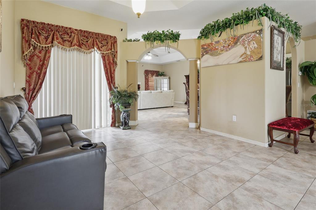A living room with tile floors, an arched entryway, and a leather recliner — 4510 BRAZILNUT AVENUE, SARASOTA, FL