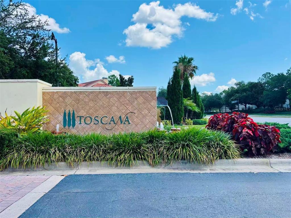 A stone monument sign for the Toscana community stands near a road with landscaping — 7174 REGINA WAY, ORLANDO, FL