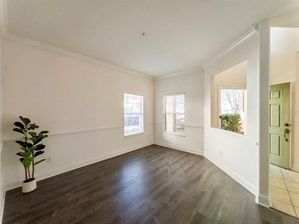 A living room with brown walls, dark wood-look flooring, a ceiling fan, and four windows — 7174 REGINA WAY, ORLANDO, FL