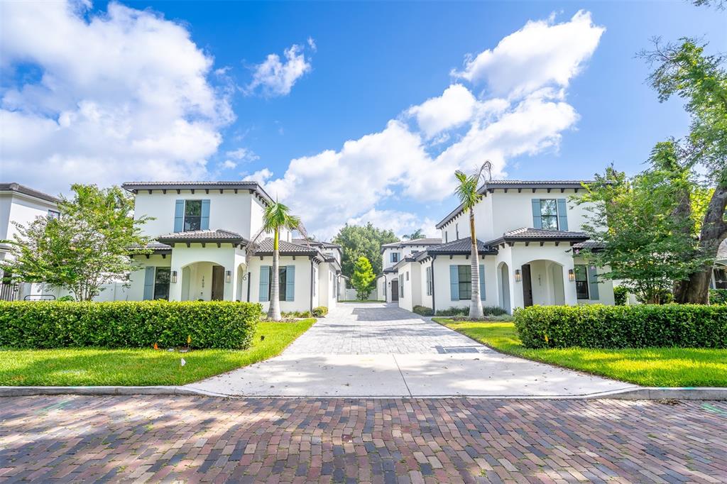 A paved driveway leads between two white two-story houses with palm trees and manicured hedges — 1411 MILLER AVENUE, WINTER PARK, FL