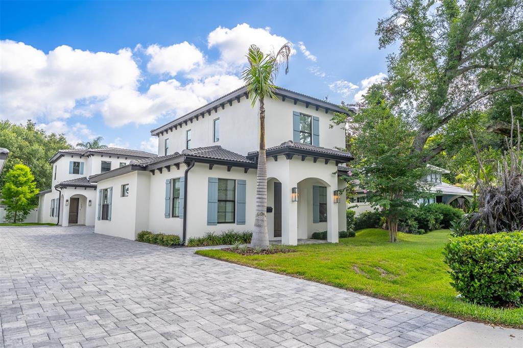 A two-story white stucco house with blue shutters and a paved driveway under a sky — 1411 MILLER AVENUE, WINTER PARK, FL