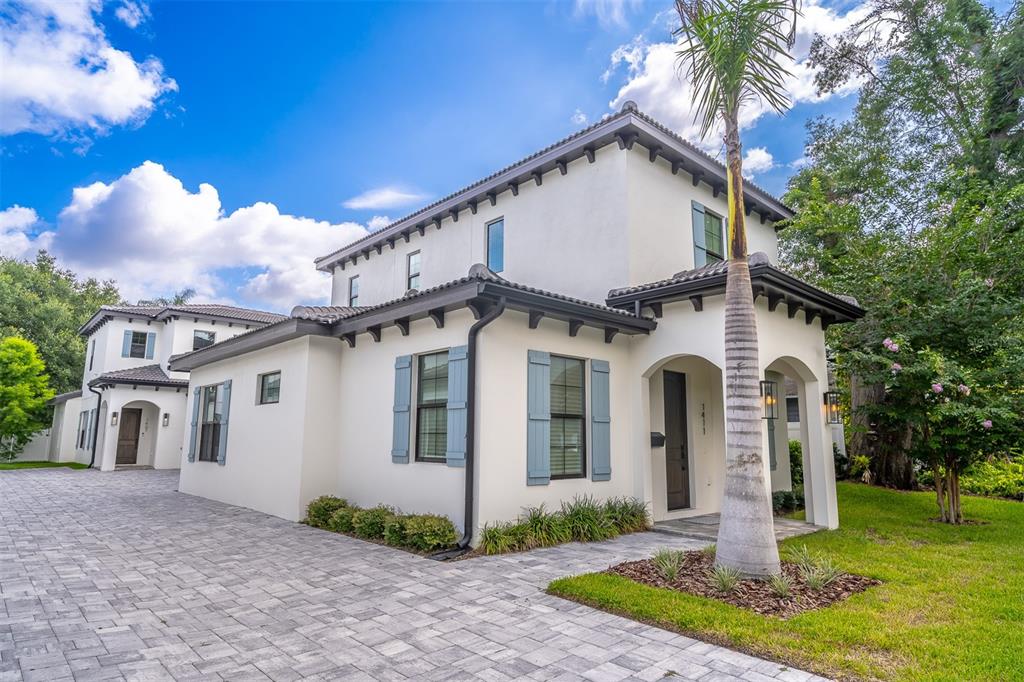 A two-story white stucco house with blue shutters and a paved driveway under a sky — 1411 MILLER AVENUE, WINTER PARK, FL