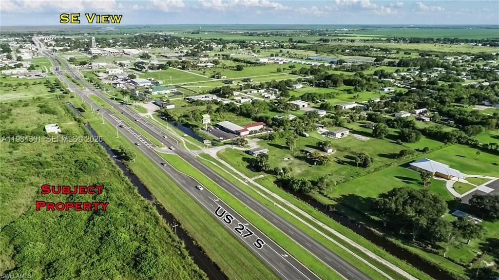 An aerial view shows a highway running through a rural landscape with scattered buildings — 1210 N U S Highway 27, Moore Haven FL 33471, MOORE HAVEN, FL