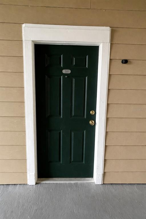 A dark green front door with the number 311 is set in a tan-sided exterior wall — 13025 MULBERRY PARK DRIVE UNIT 311, ORLANDO, FL