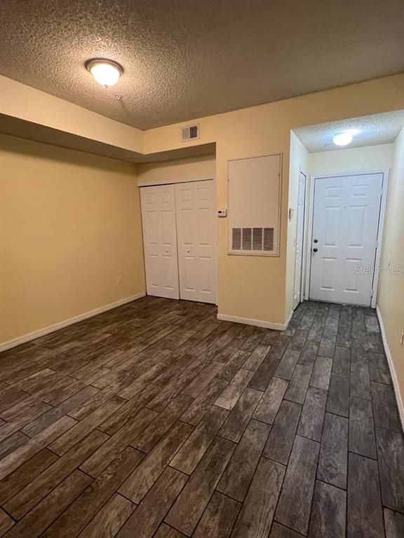 An empty room with light yellow walls, wood-look tile flooring, and a white entry door — 13025 MULBERRY PARK DRIVE UNIT 311, ORLANDO, FL