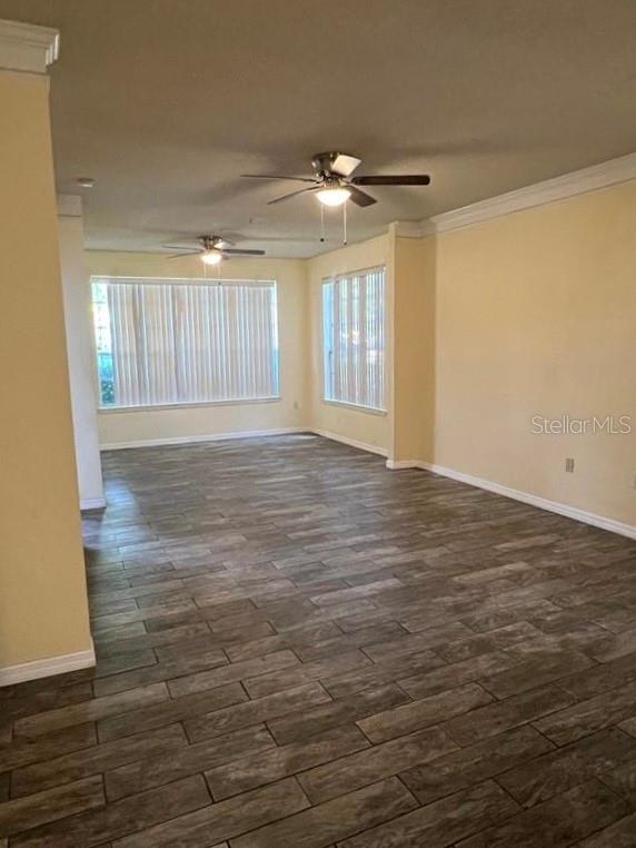 An empty living room features wood-look tile flooring, two ceiling fans, and large windows — 13025 MULBERRY PARK DRIVE UNIT 311, ORLANDO, FL