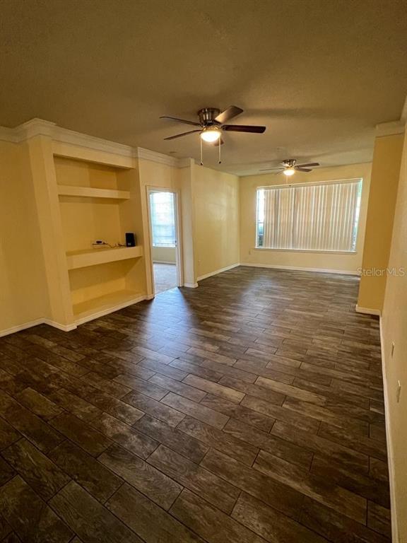 A living room features wood-look tile flooring, two ceiling fans, and a built-in wall niche — 13025 MULBERRY PARK DRIVE UNIT 311, ORLANDO, FL