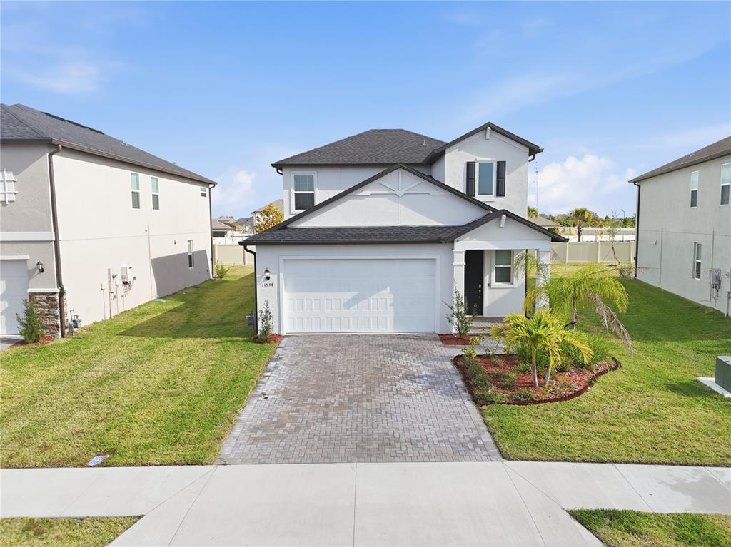 A two-story house with a white stucco exterior, dark roof, and a paved driveway — 11534 72ND PLACE E, PALMETTO, FL