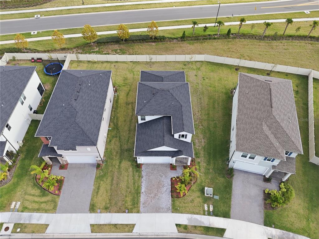 An aerial view shows three suburban houses with driveways and backyards enclosed by a fence — 11534 72ND PLACE E, PALMETTO, FL
