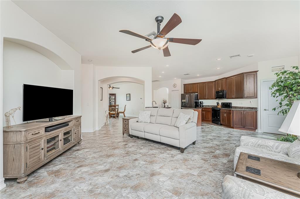 An open-concept living room features tile flooring, a ceiling fan, and an adjacent kitchen — 228 ANTILLA DRIVE, ROTONDA WEST, FL