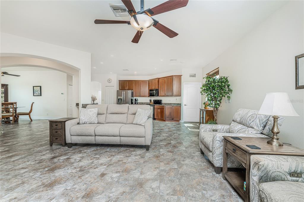 A living room with tile flooring, a ceiling fan, and an open kitchen with wood cabinets — 228 ANTILLA DRIVE, ROTONDA WEST, FL