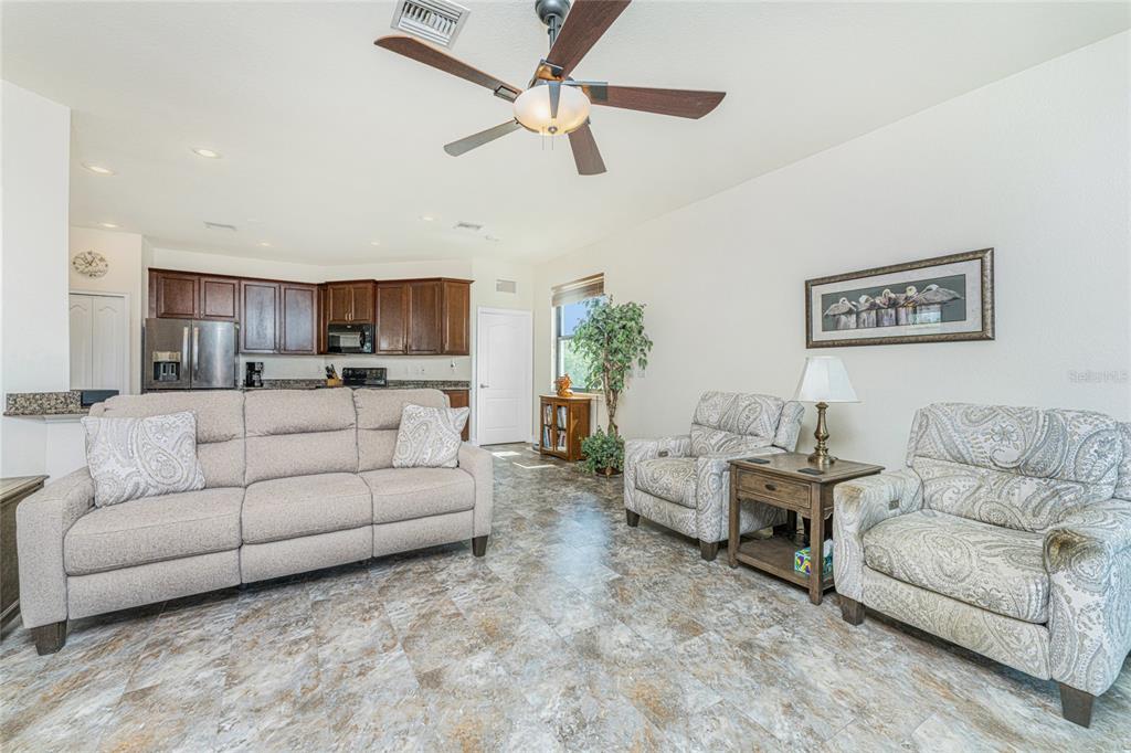 A living room with tile flooring, a ceiling fan, and an open-concept kitchen — 228 ANTILLA DRIVE, ROTONDA WEST, FL