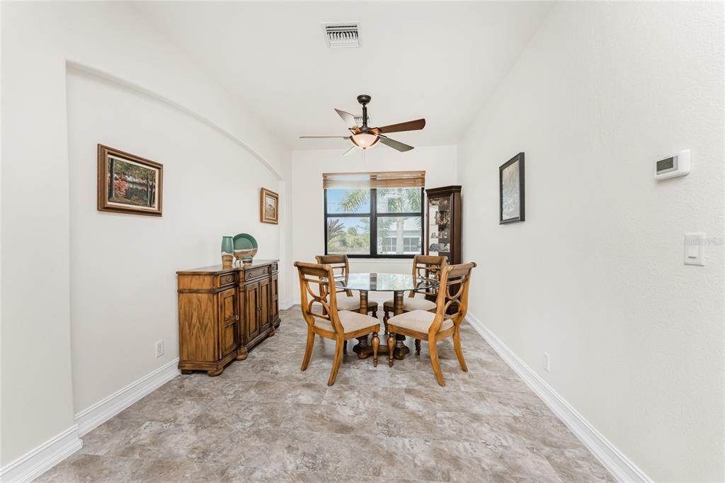 A dining room features a glass-topped table, four wooden chairs, a sideboard, and tile flooring — 228 ANTILLA DRIVE, ROTONDA WEST, FL