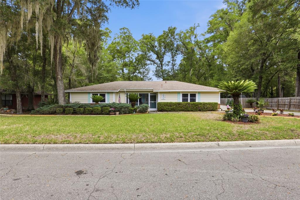 A single-story light yellow house with a shingled roof sits behind a grassy lawn — 710 SW 77TH TERRACE, GAINESVILLE, FL