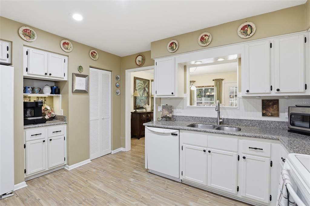 A kitchen with white cabinets, granite countertops, and a pass-through window to another room — 710 SW 77TH TERRACE, GAINESVILLE, FL