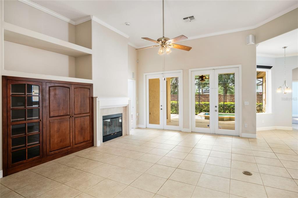 A living room features tile floors, a fireplace, built-in cabinetry, and double doors to a patio — 10734 WOODCHASE CIRCLE, ORLANDO, FL