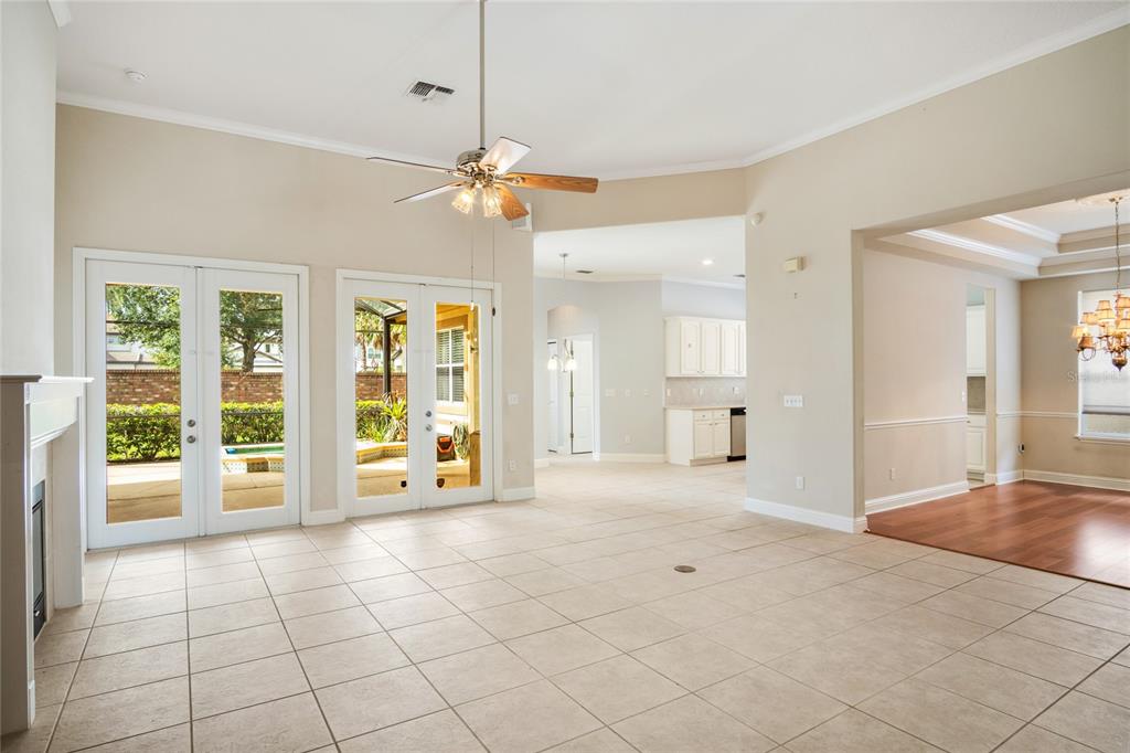 A spacious living room with tile flooring, a ceiling fan, and double doors leading outside — 10734 WOODCHASE CIRCLE, ORLANDO, FL