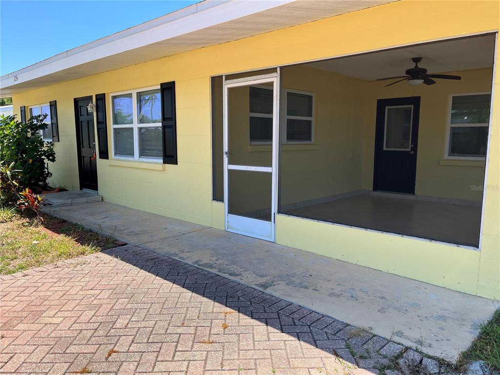 A yellow exterior wall features a screened-in porch, a black front door, and a window — 2154 INNER CASS CIRCLE, SARASOTA, FL