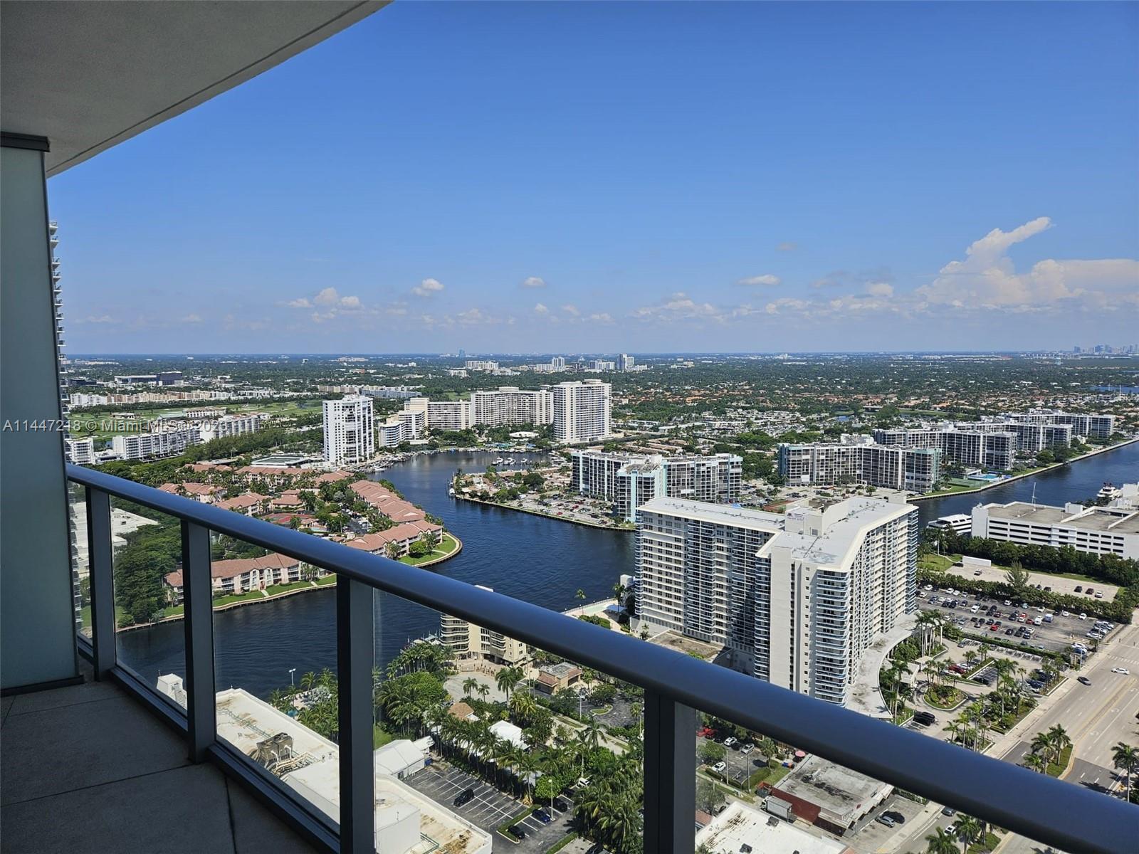 A high-rise balcony overlooks a waterway, residential buildings, and a parking lot under a blue sky — 4111 S Ocean Dr # 3308, Hollywood FL 33019, HOLLYWOOD, FL