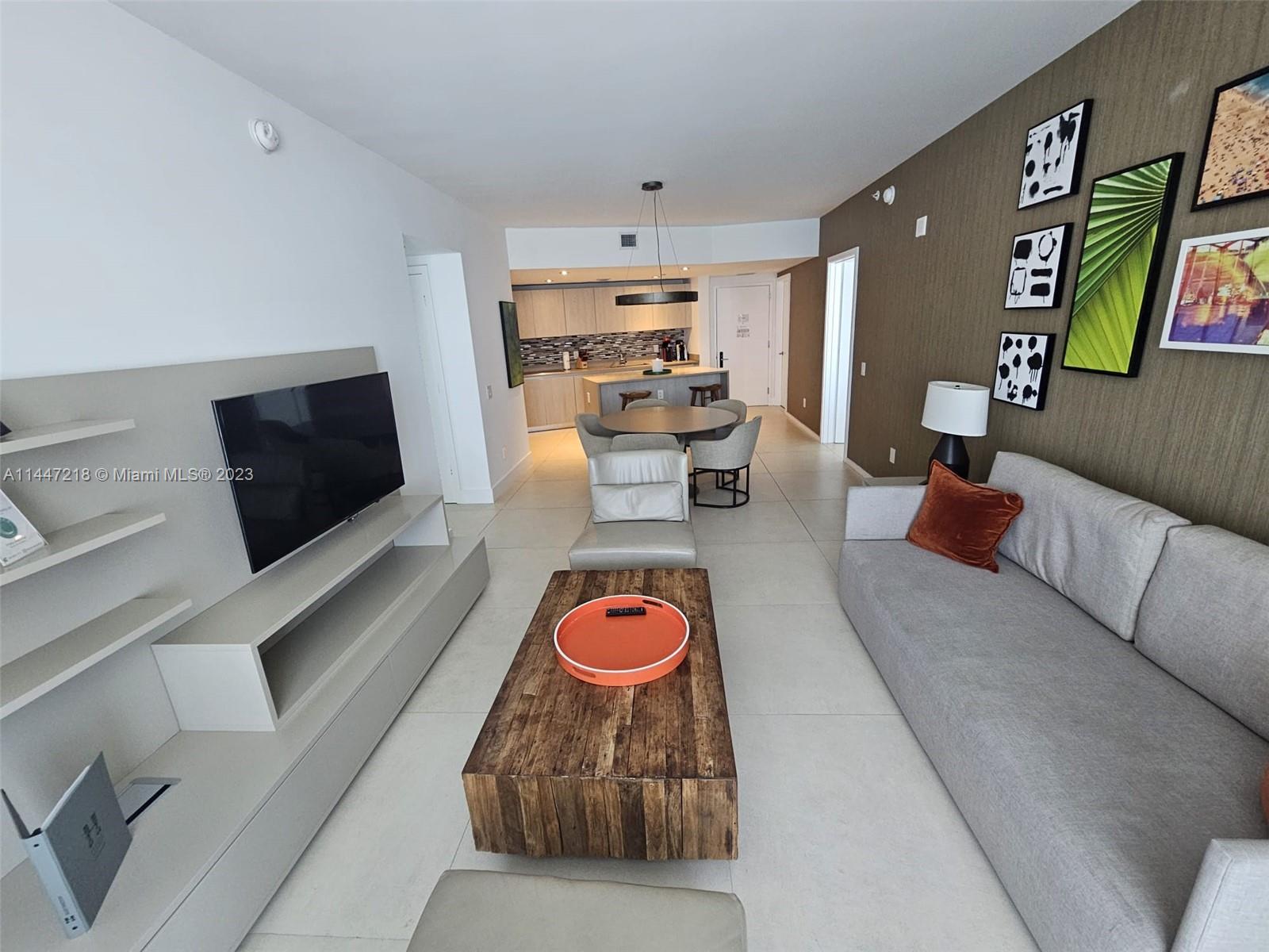 A modern living room features a gray sofa, wooden coffee table, and an open kitchen — 4111 S Ocean Dr # 3308, Hollywood FL 33019, HOLLYWOOD, FL