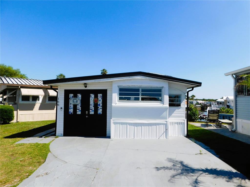 A white mobile home with a black door and a concrete driveway under a clear sky — 9000 US HIGHWAY 192 UNIT 166, CLERMONT, FL