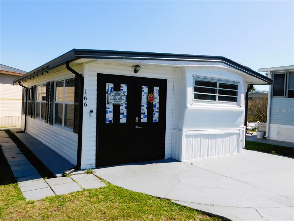 A white mobile home exterior features a black double door with decorative glass panels — 9000 US HIGHWAY 192 UNIT 166, CLERMONT, FL