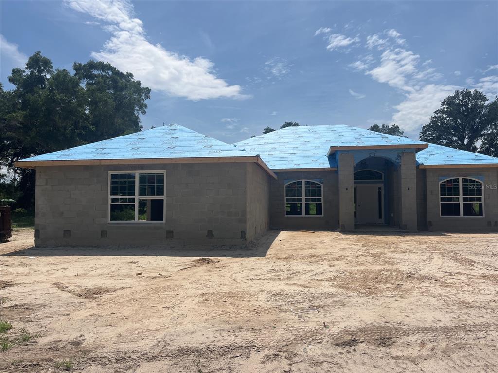 A single-story concrete block house under construction with a blue roof underlayment — 16794 SE 23RD AVENUE, SUMMERFIELD, FL