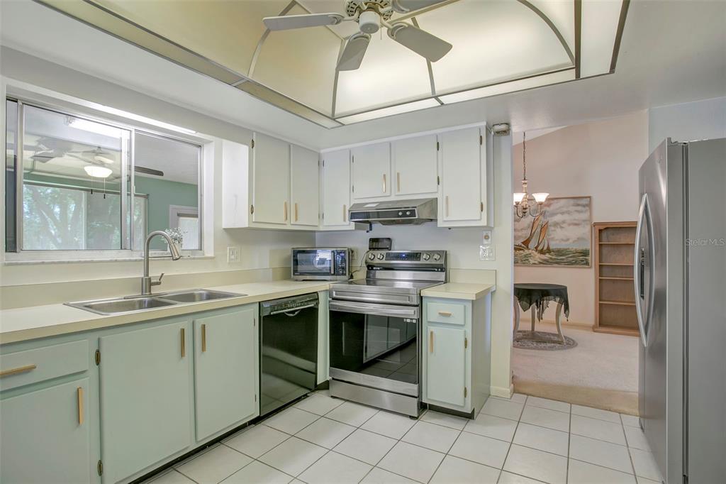 A kitchen with white cabinets, stainless steel appliances, and light-colored tile flooring — 5817 11TH AVENUE W, BRADENTON, FL
