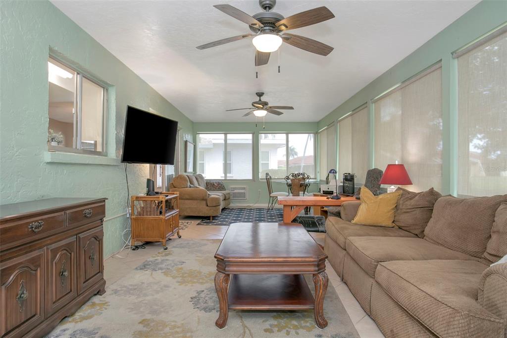 A sunroom features light green walls, two ceiling fans, a brown sofa, and tile flooring — 5817 11TH AVENUE W, BRADENTON, FL