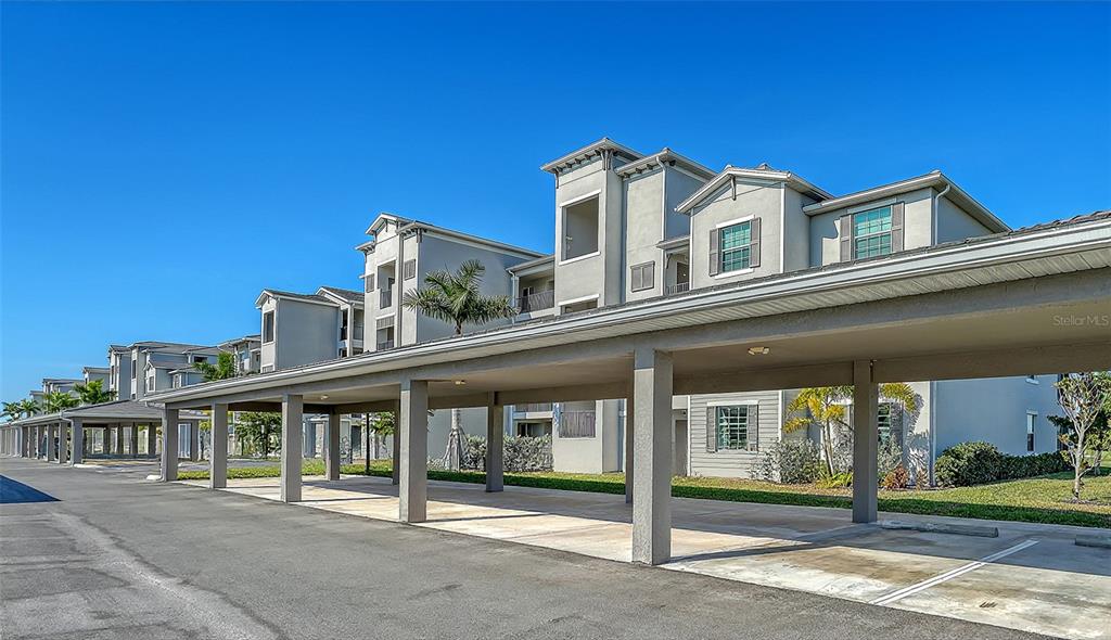 A long, covered parking structure stands in front of a multi-story apartment building — 12180 WELLEN GOLF STREET UNIT 308, VENICE, FL