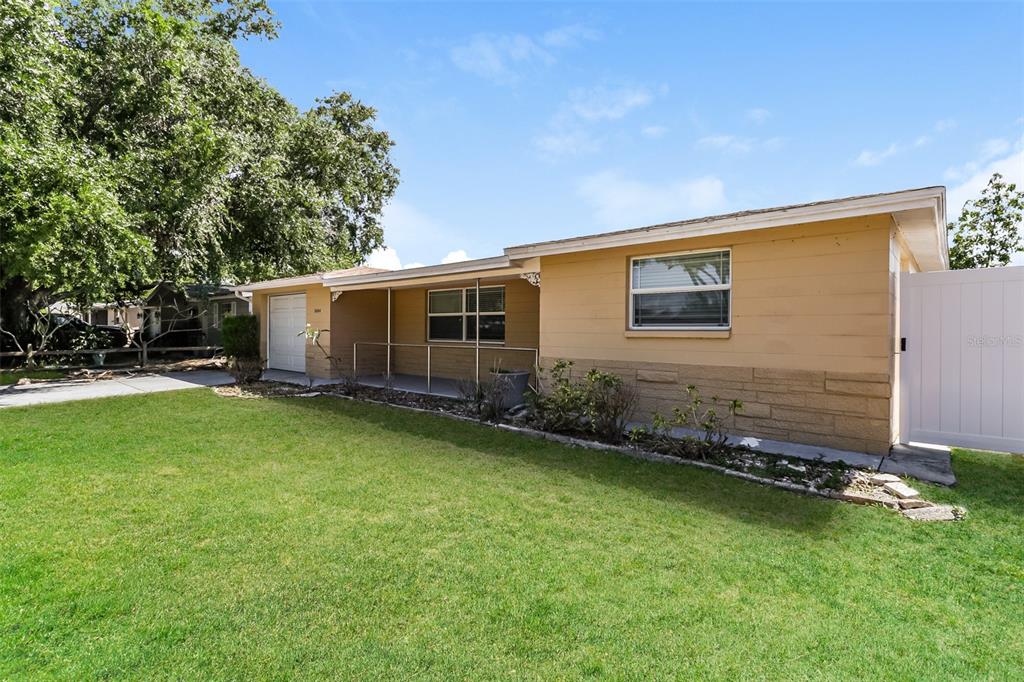 A single-story house with a tan exterior, a covered front porch, and a white gate — 3644 PANOLA DRIVE, NEW PORT RICHEY, FL