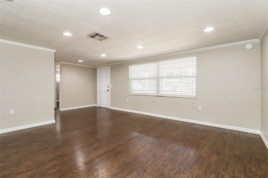 An empty room with dark wood-look flooring, light gray walls, and a large window — 3644 PANOLA DRIVE, NEW PORT RICHEY, FL