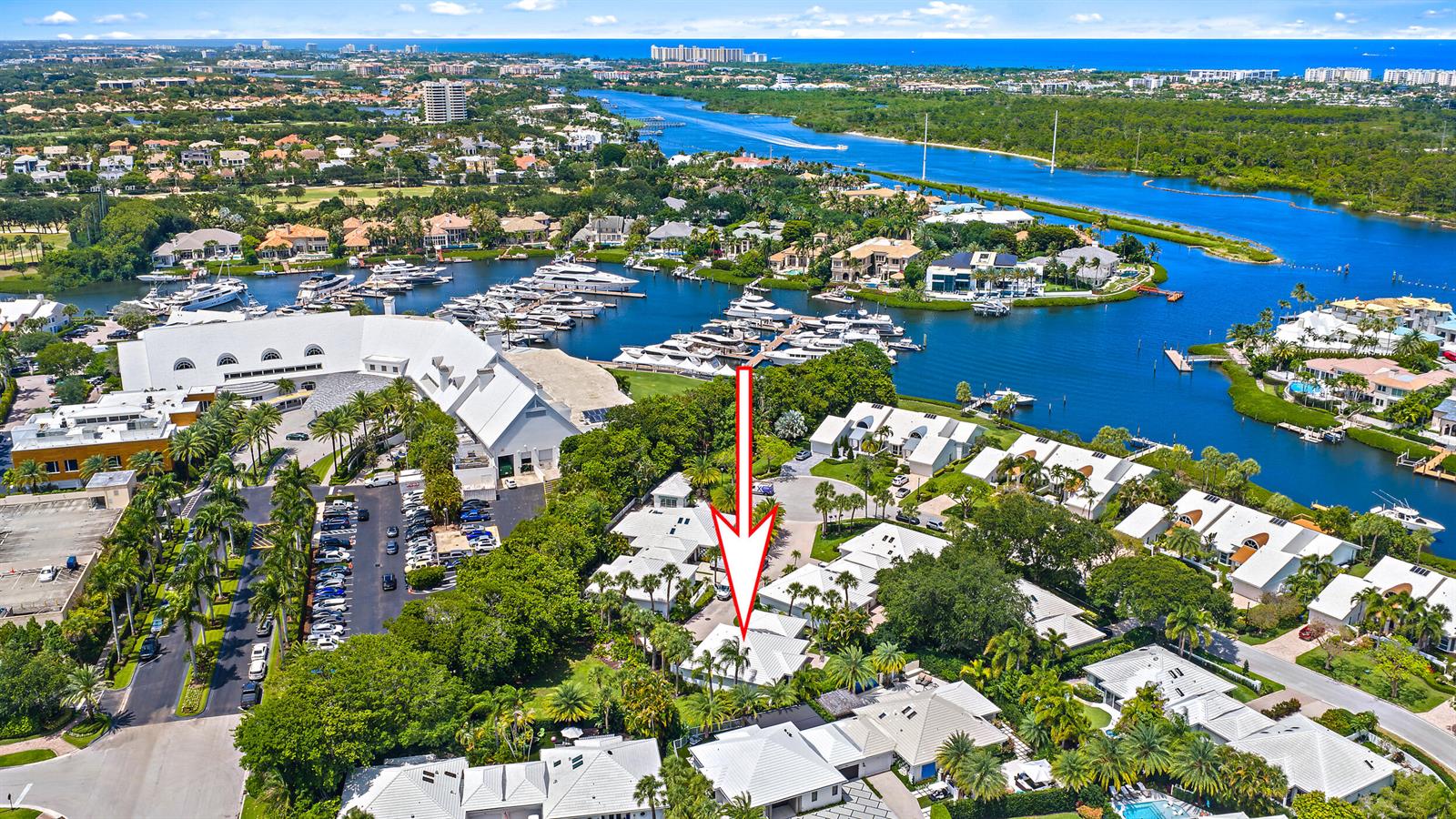 An aerial view shows a residential neighborhood with white-roofed houses near a marina and waterway — 4501 Captains Way, Jupiter FL 33477, JUPITER, FL