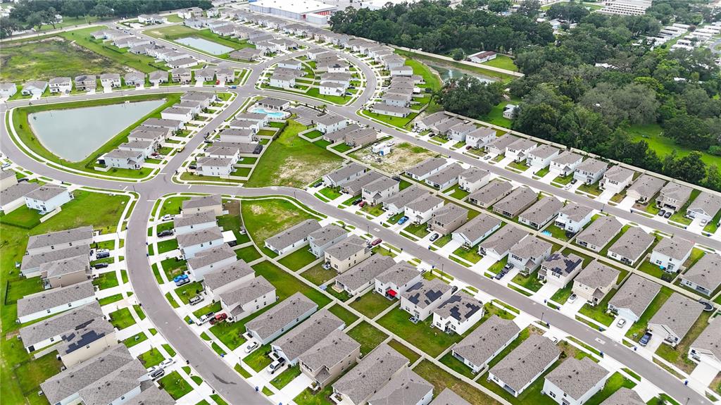 An aerial view shows a suburban neighborhood with numerous houses, paved streets, and retention ponds — 4409 SAND DOLLAR WAY, ZEPHYRHILLS, FL