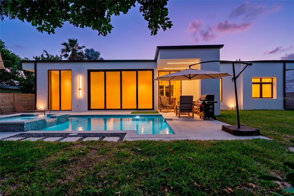 A modern house exterior features a swimming pool, patio furniture, and large glass sliding doors — 2441 WEBBER STREET, SARASOTA, FL