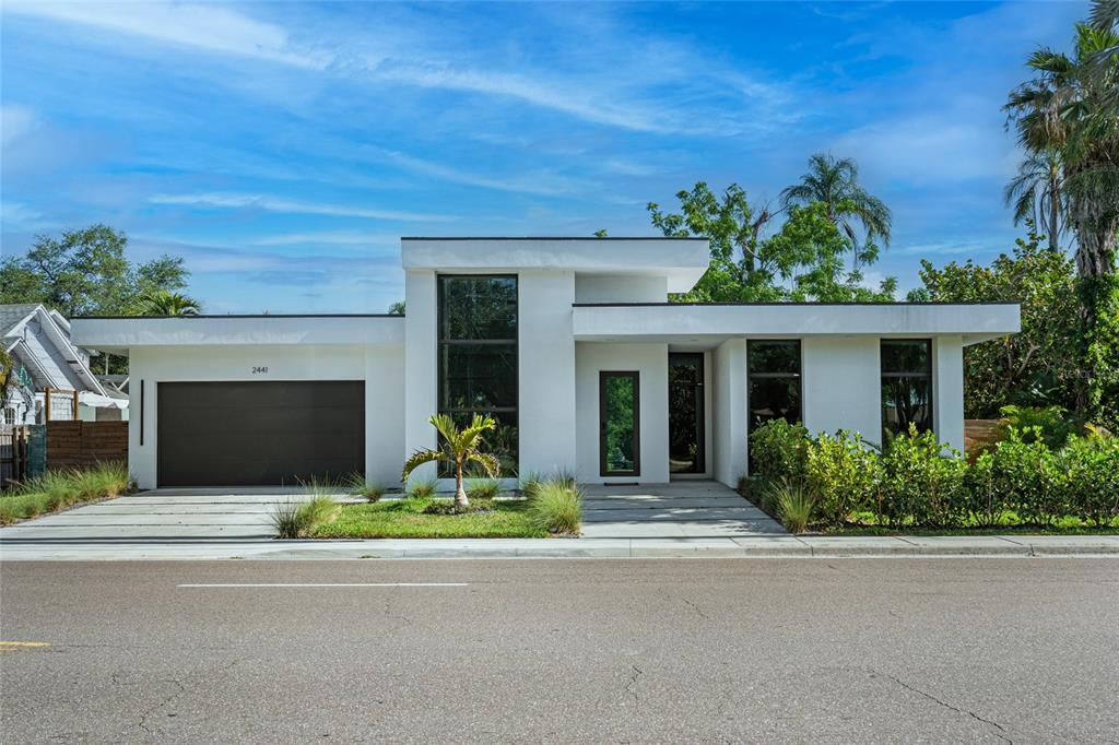 A modern, flat-roofed, white single-story house with a dark garage door and large windows — 2441 WEBBER STREET, SARASOTA, FL