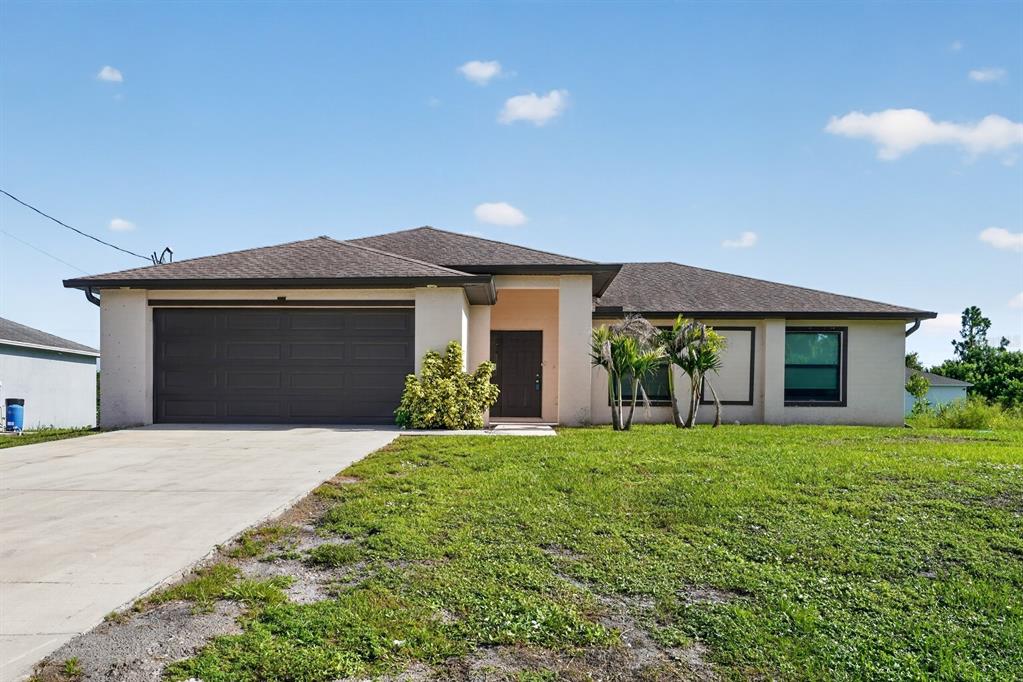 A single-story house with a brown garage door, tan stucco exterior, and a concrete driveway — 2712 15TH STREET SW, LEHIGH ACRES, FL