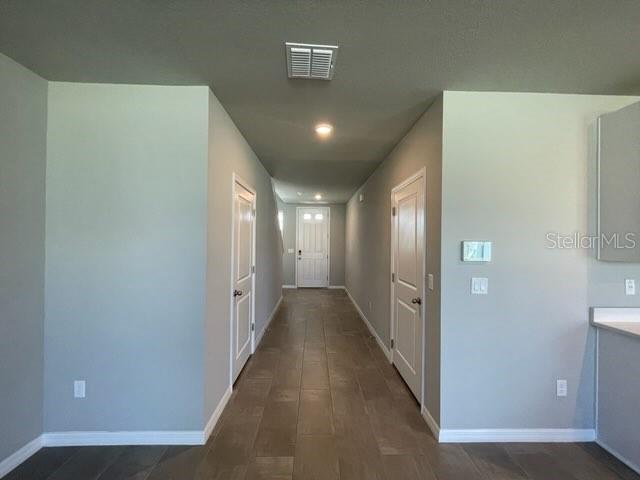 A hallway with light gray walls, tile flooring, and white doors leads to an entryway — 3314 FRESNO PL, ZEPHYRHILLS, FL