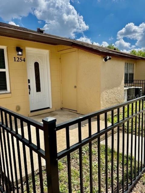 The exterior of a yellow house features a white front door and a black fence — 1254 SOPHIE BOULEVARD, ORLANDO, FL