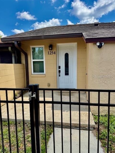 A beige concrete block house features a white front door and a black metal fence — 1254 SOPHIE BOULEVARD, ORLANDO, FL