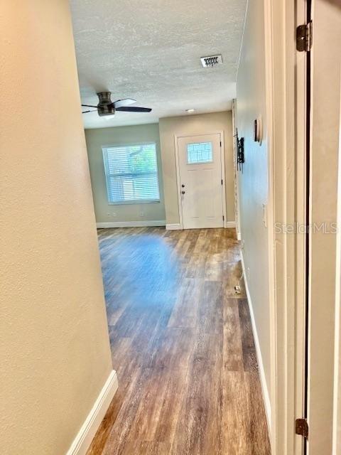 A hallway with wood-look flooring leads to a white front door and a windowed room — 1254 SOPHIE BOULEVARD, ORLANDO, FL