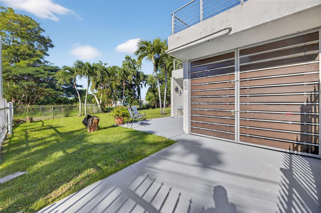 A concrete patio sits beside a modern building with horizontal wood-slatted garage doors — D-1-20 CALLE CAMBIJA, RINCON, PR