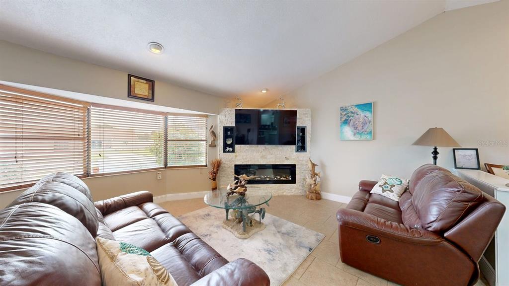 A living room features two brown leather sofas, a fireplace, and a large window — 12 CLASSIC COURT S, PALM COAST, FL
