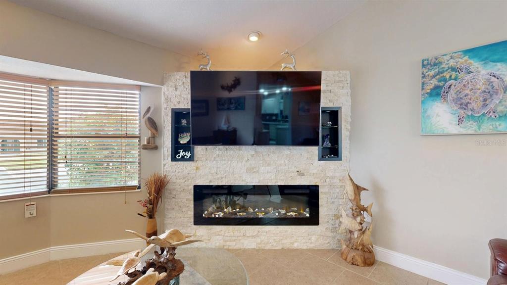 A living room features a stone fireplace wall with a mounted television and built-in shelving — 12 CLASSIC COURT S, PALM COAST, FL